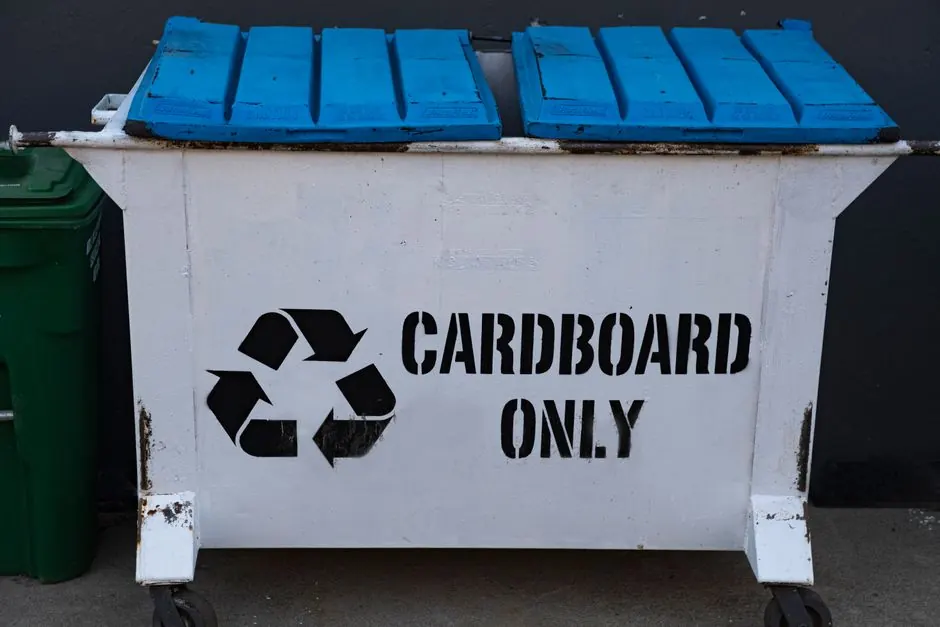 A white recycling container marked "Cardboard Only", featuring a blue lid and recycling symbol.