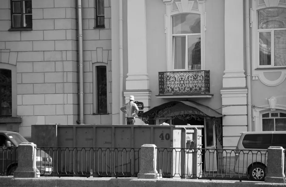 Black and white image of an urban street scene with historical architecture and a construction worker.