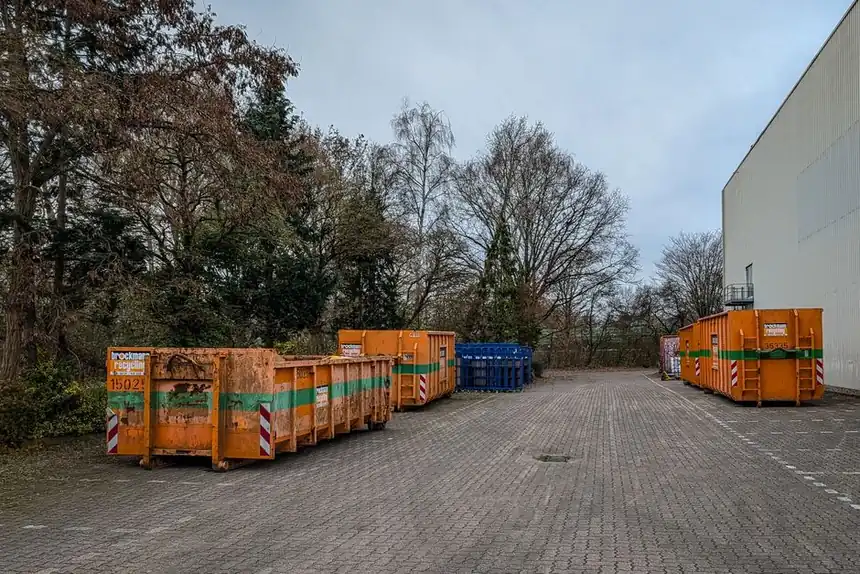 Outdoor view of industrial waste bins lined up beside a warehouse in winter.